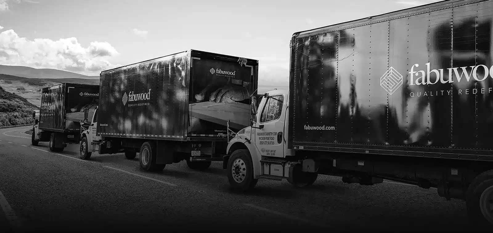Black-and-white photo of Fabuwood-branded delivery trucks on a highway